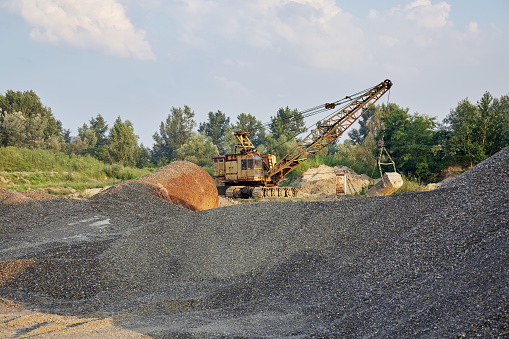 Crawler-mounted excavator in gravel canyon.